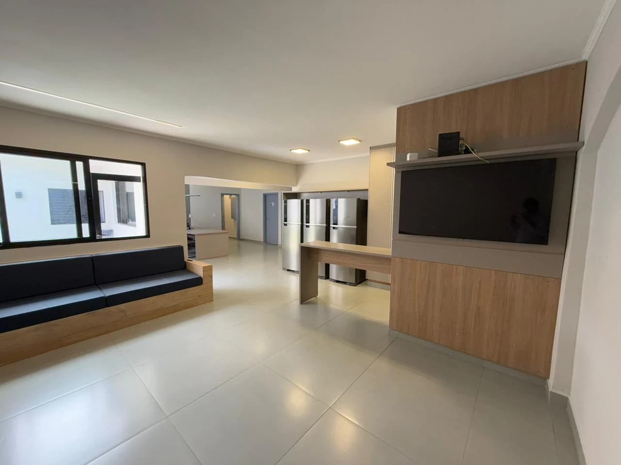 Sala de convivência com sofás e painel de televisão