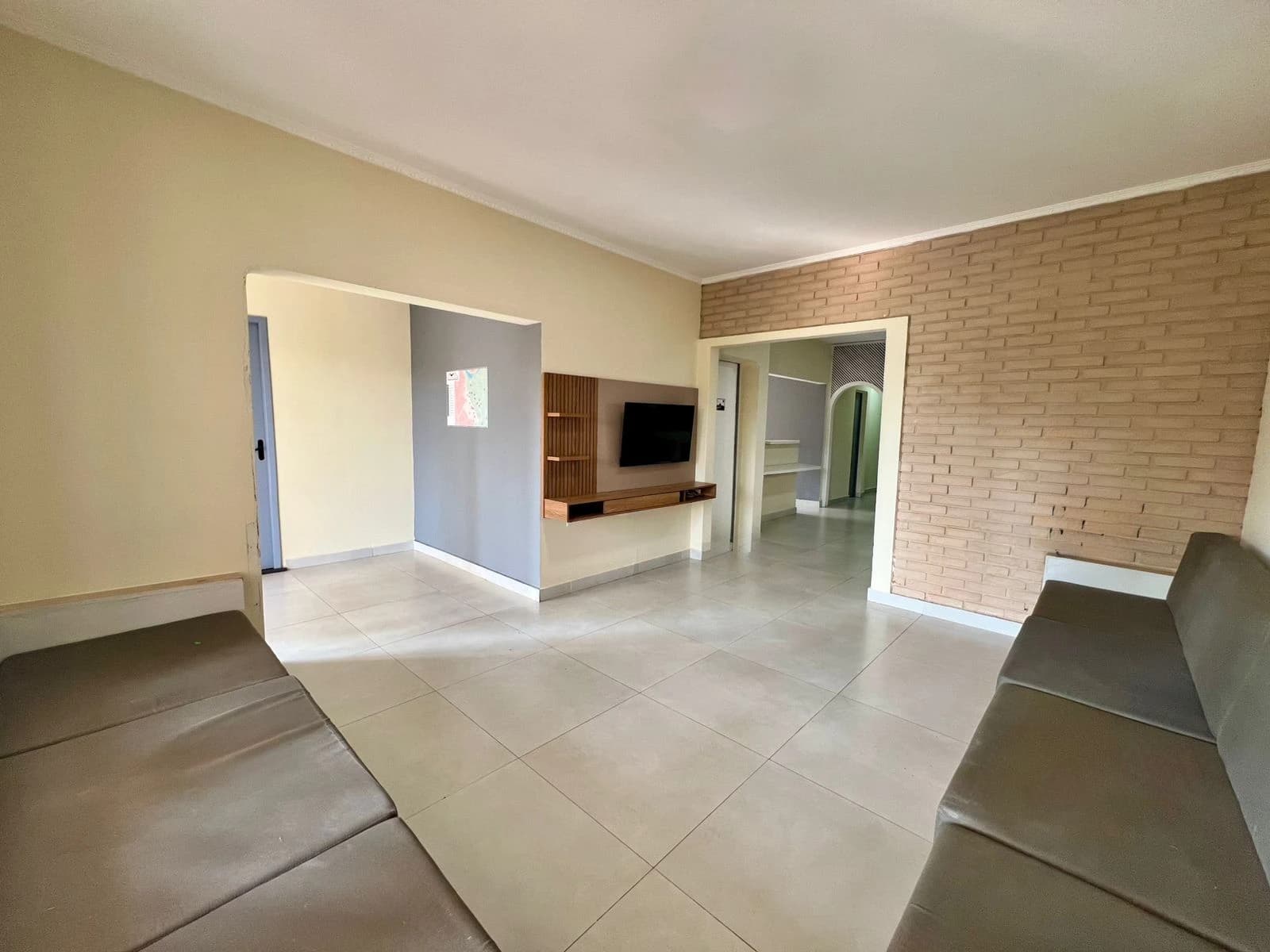 Sala de estar com sofá cinza e passagem para outros ambientes