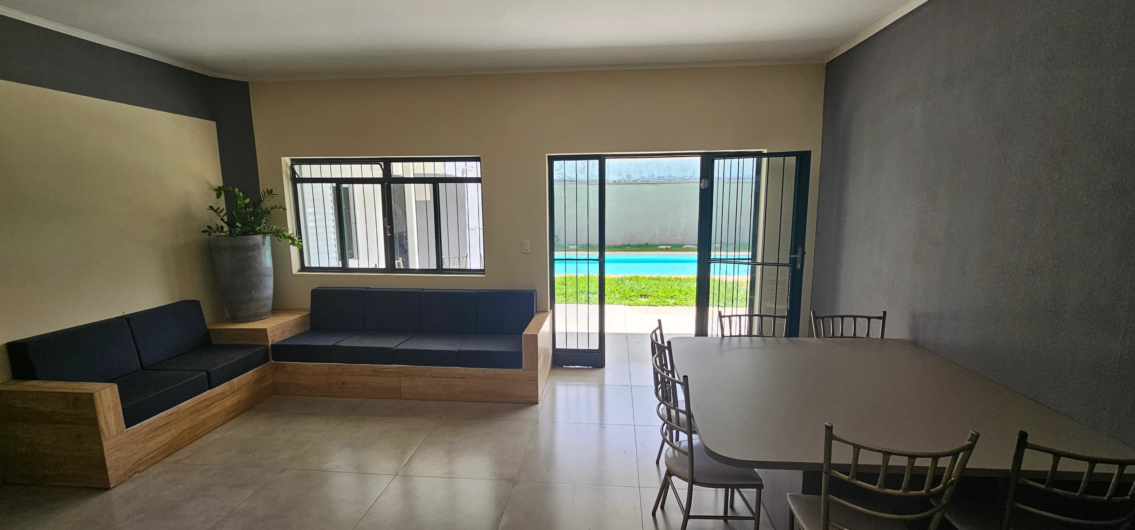 Sala com sofás, mesa de jantar e acesso ao jardim