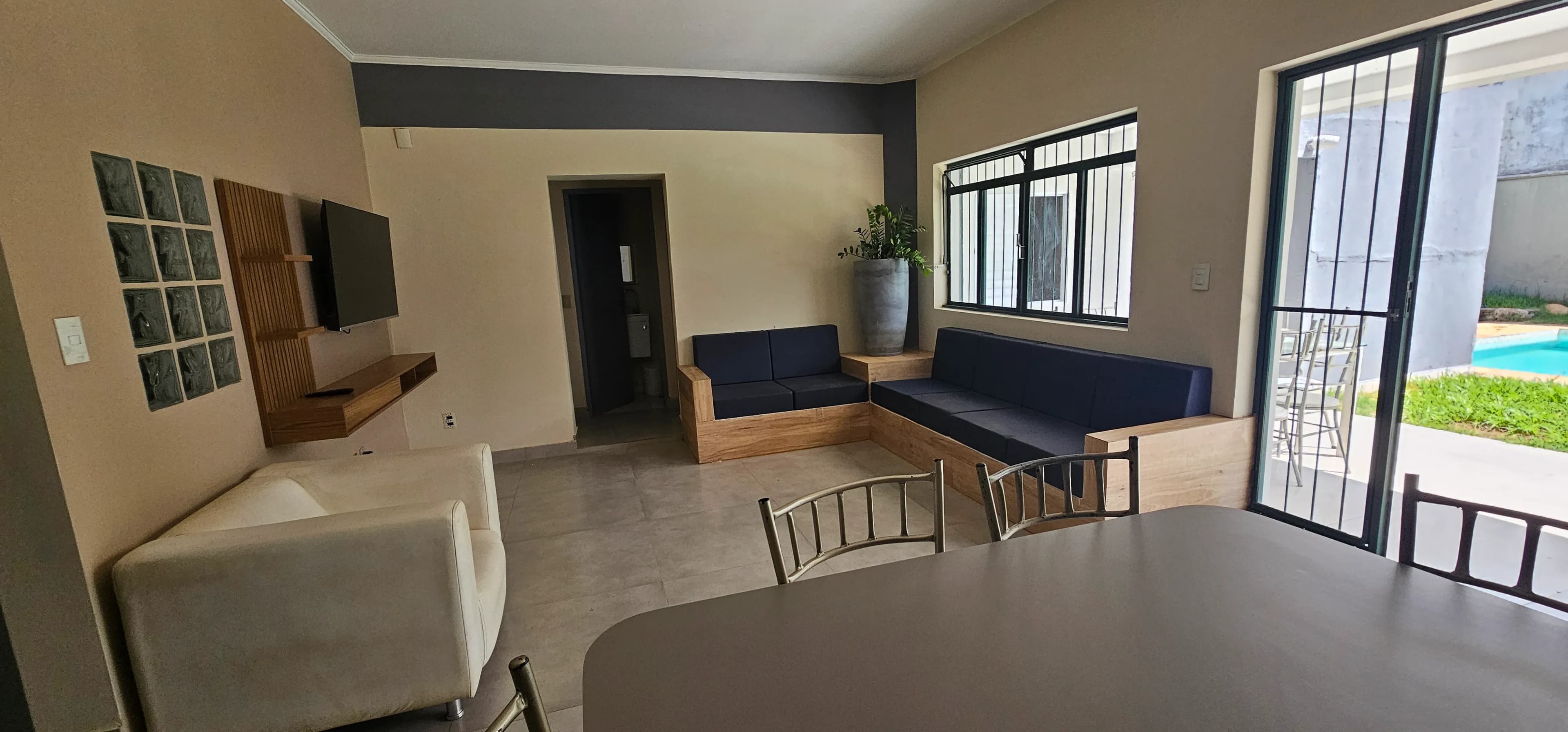 Sala de televisão e jantar com portas de vidro para o jardim
