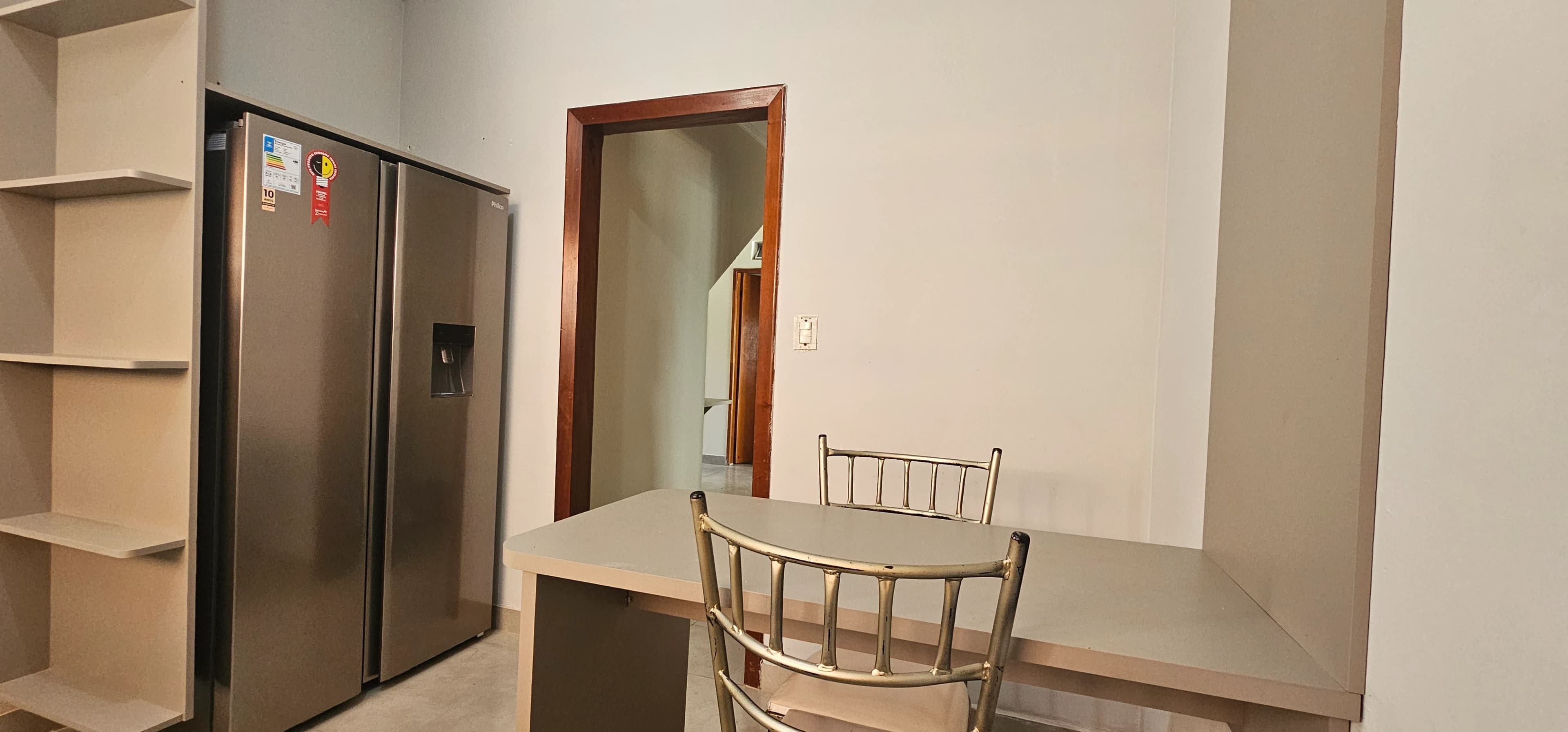 Cozinha com bancada, cadeiras e geladeira